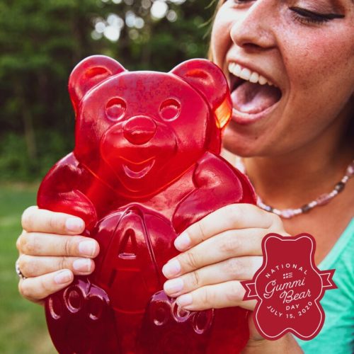 A woman playfully poses with a giant red gummy bear, celebrating National Gummy Bear Day on July 15, 2019.