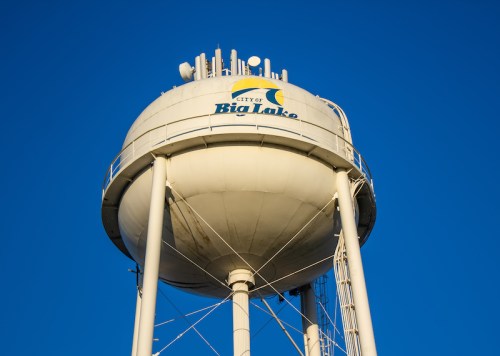 Water tower with "City of Big Lake" logo against a clear blue sky.