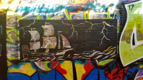 A colorful graffiti mural featuring a ship sailing through stormy waters with lightning in the background.