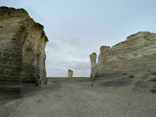 A barren landscape featuring tall, eroded rock formations under a cloudy sky.