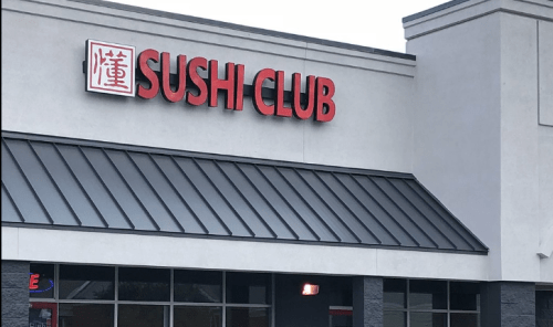 Sign for "Sushi Club" on a restaurant building with a modern design.