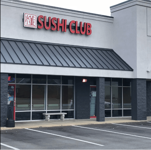 Exterior of a restaurant named "Sushi Club," featuring large red signage and a modern building design.