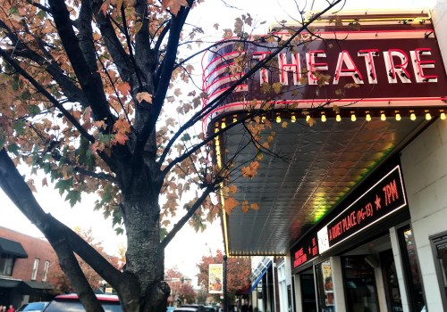 A theater marquee with bright lights, surrounded by autumn leaves on a tree, in a charming street setting.