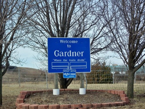 Welcome sign for Gardner, featuring the phrase "Where the trails divide," surrounded by bare trees.