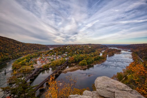 A scenic view of a river winding through autumn-colored hills, with a small town nestled along the shore.