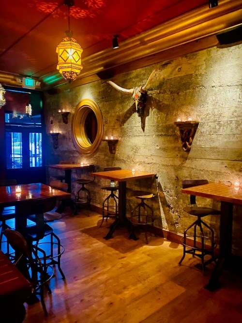 Cozy restaurant interior with wooden tables, candlelight, and a decorative bull skull on a textured wall.