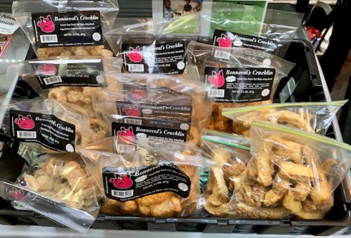 A display of packaged pork cracklins in clear bags, labeled "Bonnema's Cracklin," arranged in a black basket.
