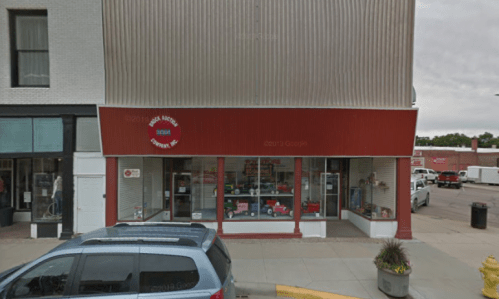 A storefront with a red awning and large windows displaying toys and children's items, located on a city street.