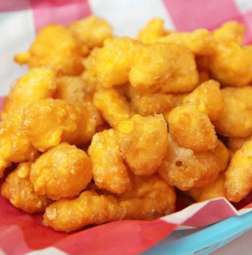 A close-up of golden, crispy popcorn chicken served in a red and white checkered basket.