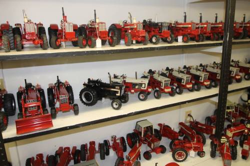 A display of various red toy tractors arranged on shelves, showcasing different models and sizes.