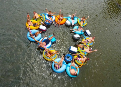A group of people floating in a circle on colorful inner tubes in a river, enjoying a sunny day.