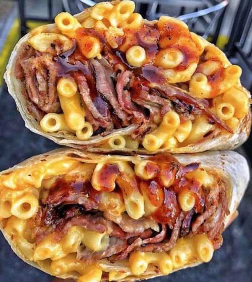 A close-up of a burrito filled with macaroni, beef, and barbecue sauce, showcasing its rich, layered ingredients.