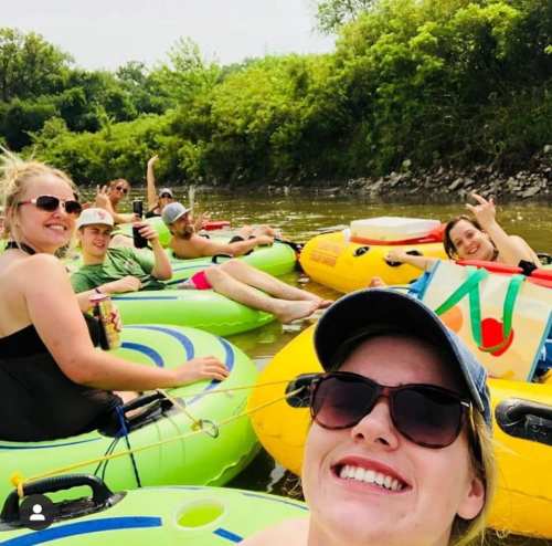A group of friends enjoying a sunny day floating on colorful inner tubes in a river, smiling and having fun.