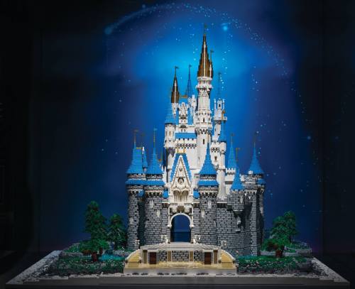 A detailed LEGO model of a castle with blue roofs and golden spires, set against a starry background.