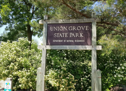 Sign for Union Grove State Park surrounded by greenery and flowers, indicating the Department of Natural Resources.