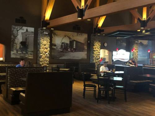 Interior of a restaurant with wooden beams, stone walls, and booths. Black-and-white photos decorate the walls.