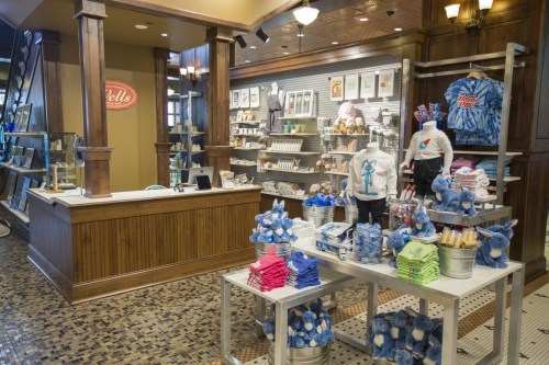 A cozy retail shop featuring merchandise displays, a checkout counter, and colorful clothing and souvenirs.