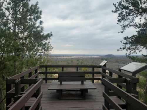 View from a wooden observation deck overlooking a vast landscape under a cloudy sky.