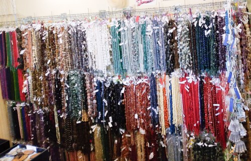 A colorful display of various beaded strands hanging on hooks, showcasing a range of materials and colors.