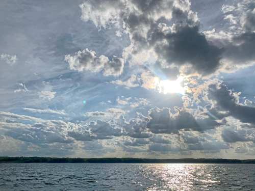 A serene lake scene with sunlight breaking through clouds, reflecting on the water's surface.