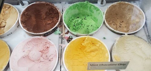A display of various ice cream flavors in tubs, including chocolate, mint chocolate chip, and vanilla.