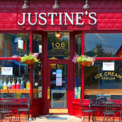 Bright red storefront of Justine's Ice Cream Parlor, featuring hanging flower baskets and outdoor seating.
