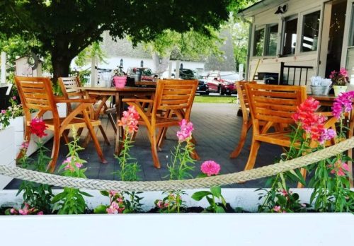 A cozy outdoor seating area with wooden chairs and colorful flowers in a garden setting.