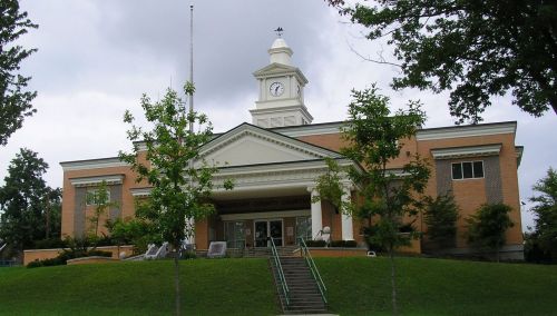 A brick building with a clock tower, surrounded by trees and a grassy area, likely a county courthouse.