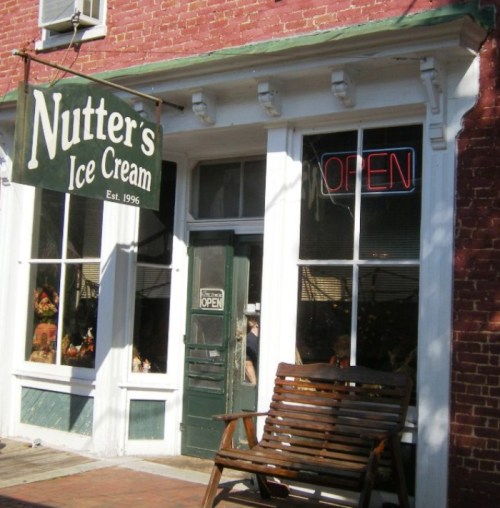 Exterior of Nutter's Ice Cream shop with a green door, open sign, and a wooden bench outside.