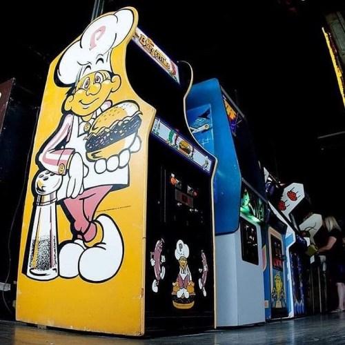 A colorful vintage arcade game featuring a cartoon chef holding a burger, with other arcade machines in the background.