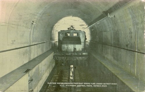 Electric train emerging from a tunnel under the Detroit River, with "Michigan Central Train, Detroit, Mich." caption.
