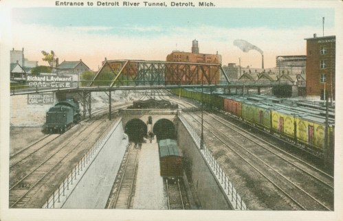 Vintage postcard showing the entrance to the Detroit River Tunnel, with trains and industrial buildings in the background.