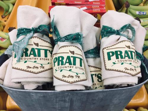 A metal bucket filled with neatly rolled towels, each labeled "Pratt's Country Store, Fun City, TN."