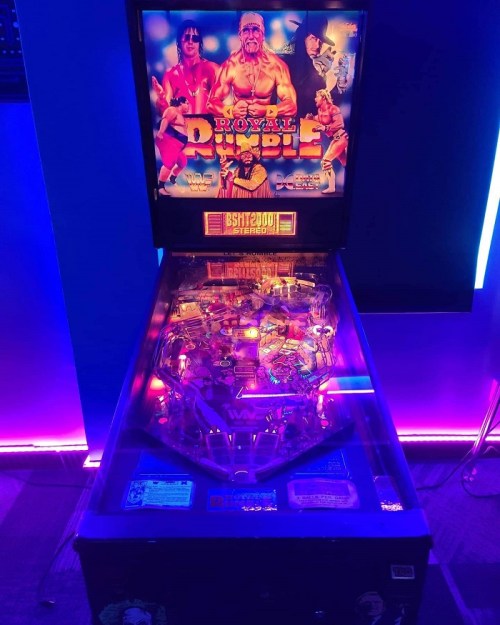 A brightly lit pinball machine featuring a wrestling theme, titled "Royal Rumble," with colorful graphics and neon lights.