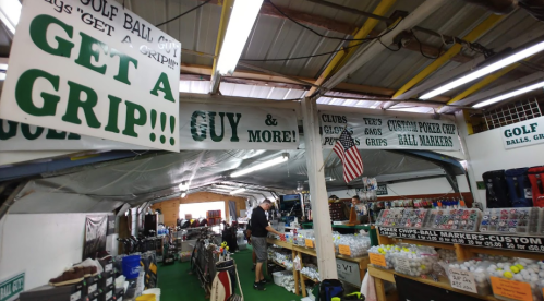 Interior of a golf shop with signs promoting grips and custom ball markers, featuring various golf equipment and accessories.