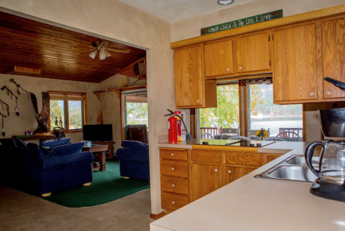 Cozy kitchen with wooden cabinets, leading to a living area with blue sofas and a view of the outdoors.