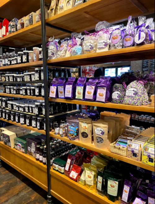 Shelves filled with various packaged foods and products, including jars, bags, and boxes, in a store setting.