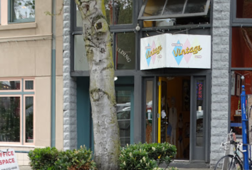 A storefront with a sign reading "Vintage" and an open sign, next to a tree and a bicycle parked outside.