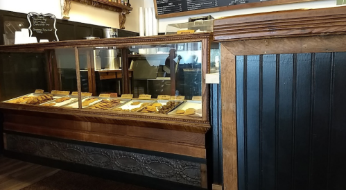A wooden display case filled with various baked goods in a cozy café setting.