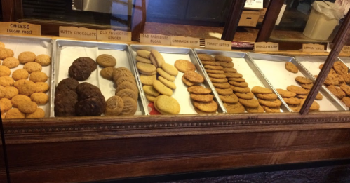 A display case filled with various types of cookies, including chocolate chip, peanut butter, and ginger cookies.