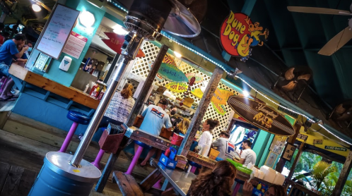 A colorful outdoor eatery with people dining, featuring bright decor and a lively atmosphere.