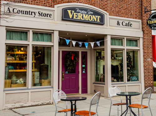 A charming country store and café with a purple door, festive decorations, and outdoor seating.