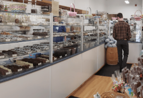 A chocolate shop interior with glass displays filled with various confections and a customer browsing.