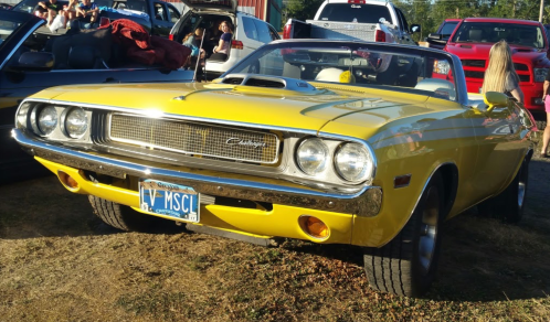 A classic yellow convertible car parked outdoors, showcasing its sleek design and chrome details.
