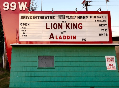 A drive-in theater marquee displaying "The Lion King" and "Aladdin" with showtimes for Friday, Saturday, and Sunday.