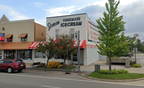 A storefront for "Janet's Homemade Ice Cream" with a striped awning and colorful flowers in front.