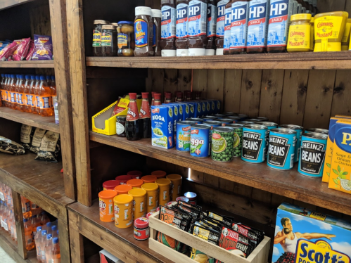 Shelves stocked with various condiments, canned goods, and snacks in a rustic wooden display.