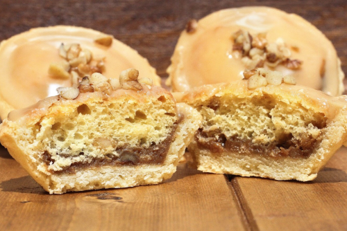 Close-up of a cut dessert revealing a soft, nut-topped filling inside a golden pastry shell.