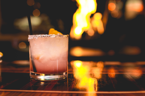 A refreshing cocktail with ice and a slice of orange, set against a warm, glowing background.