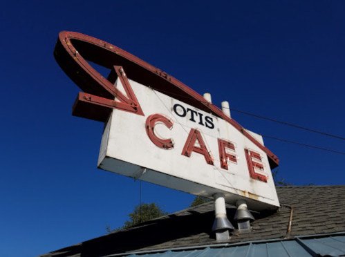 Sign for Otis Cafe with a retro design against a clear blue sky.